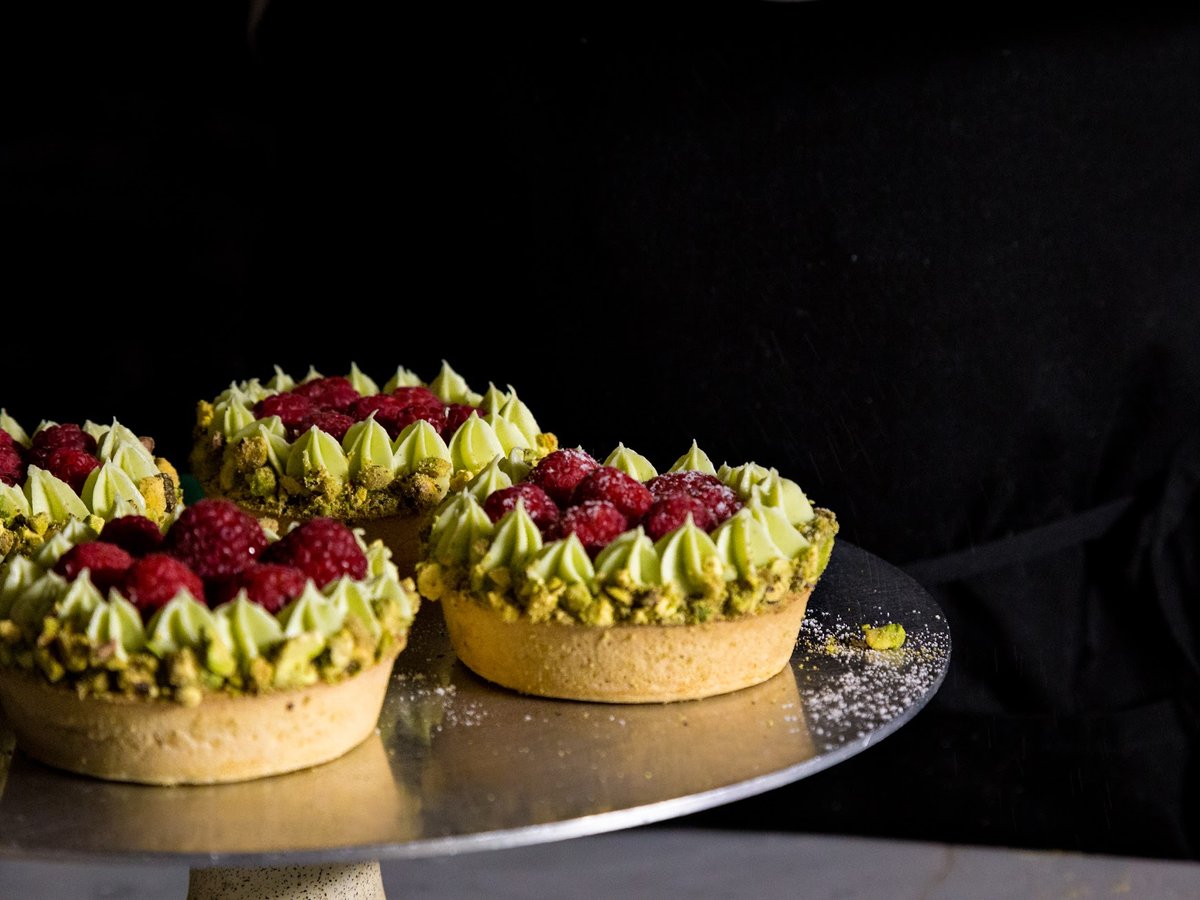 Tartelettes à la crème de pistache et aux framboises, sur fond noir